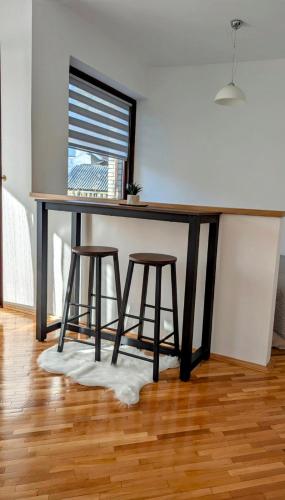 a table with two stools under a table with a window at Apartman Karingtonka free parking in Vranje