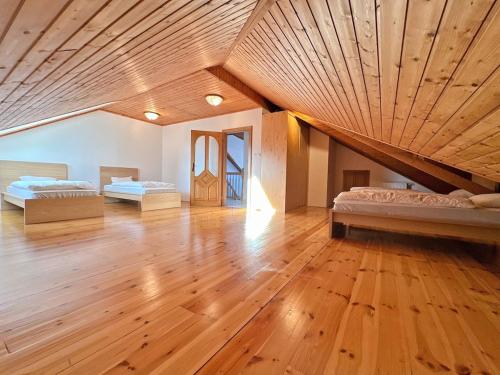 two beds in a large room with a wooden ceiling at Vila Baška in Frýdek-Místek