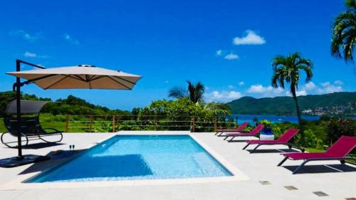 a swimming pool with chairs and an umbrella at Magnifique villa piscine vue mer à 180 in Sainte-Anne