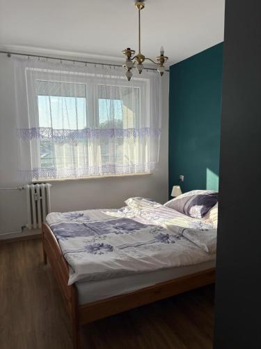 a bedroom with a bed with a blue wall and a window at Zamkowa in Sanok