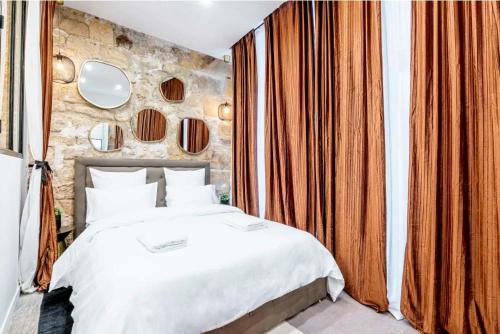 une chambre avec un lit blanc et un mur en pierre dans l'établissement Keyz - Spacious 2BD in the heart of Le Marais, à Paris