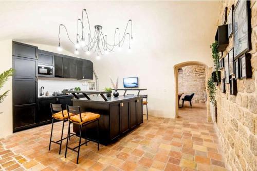 - une cuisine avec un bar avec des chaises et un lustre dans l'établissement Keyz - Spacious 2BD in the heart of Le Marais, à Paris
