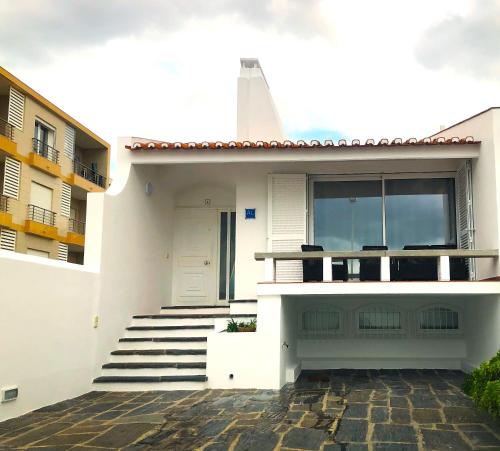 a white house with stairs and a white door at Casa do Mar -Sea house in Nazaré