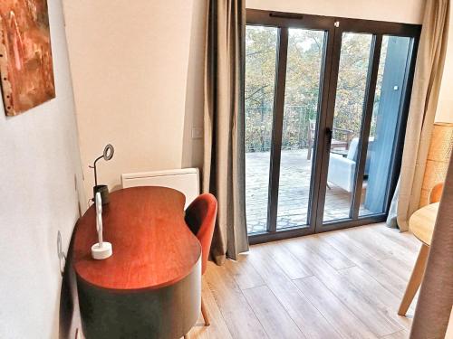 a table and a chair in a room with a sliding glass door at Au sommet des Ocres et des Bois - Maison T3 & Parking in Roussillon