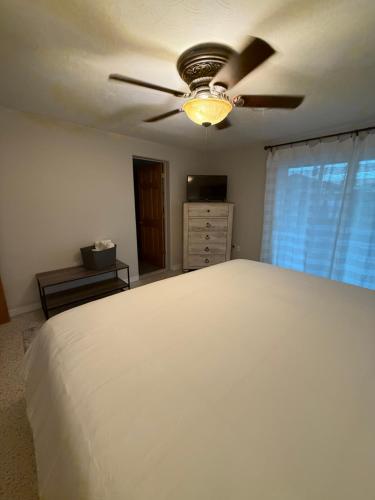 a bedroom with a white bed and a ceiling fan at Pool home on the Bay, large private yard near AMI in Bradenton