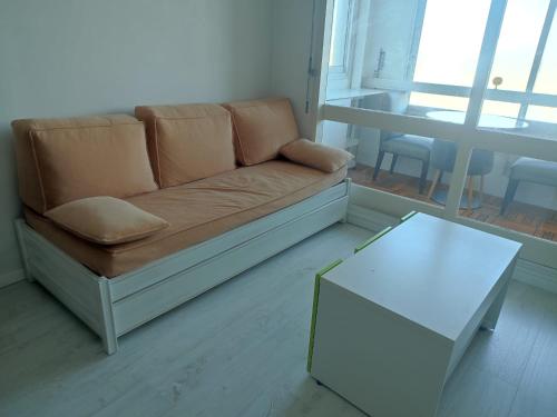 a living room with a couch and a table at Appartement vue sur mer & le port de Courseulles-sur-Mer in Courseulles-sur-Mer