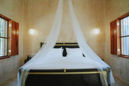 a bed with a canopy in a room with windows at Hacienda Cenote San Ignacio in Chocholá