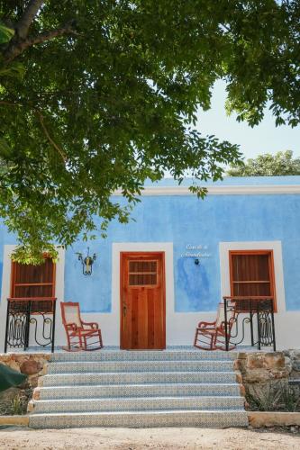 a blue and white building with stairs and chairs at Hacienda Cenote San Ignacio in Chocholá