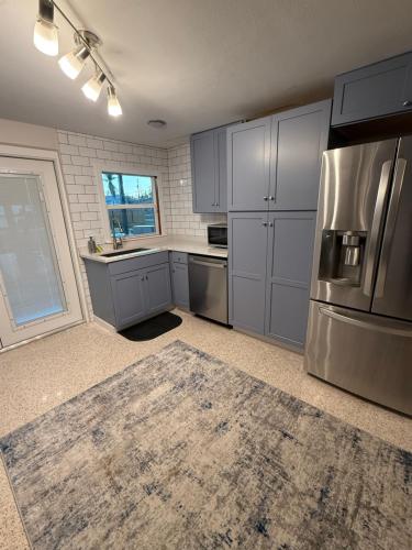 a kitchen with gray cabinets and a stainless steel refrigerator at Pool home on the Bay, large private yard near AMI in Bradenton