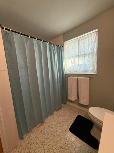 a bathroom with a shower curtain and a toilet at Pool home on the Bay, large private yard near AMI in Bradenton
