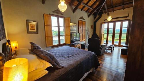 a bedroom with a large bed in a room with windows at Pousada Borghetto – Charme e Exclusividade no Vale dos Vinhedos in Bento Gonçalves