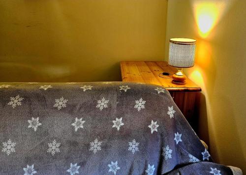 a bed with a blanket with snowflakes on it next to a table at Piste Terminillo Appartamento Centro in Terminillo