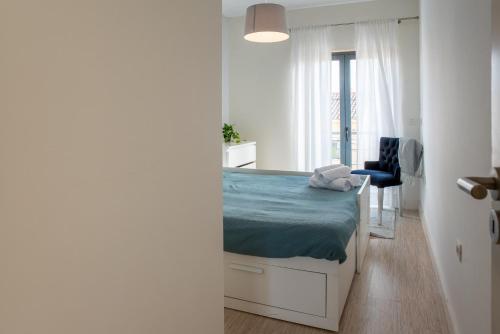 a small bedroom with a bed and a chair at Villa Turquesa Estoril in Alcabideche