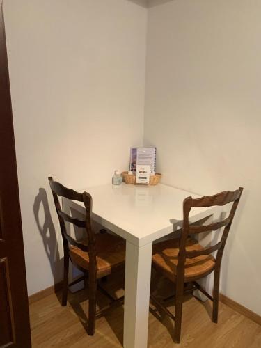 une table blanche avec deux chaises et une boîte dessus dans l'établissement Gite Chez Joséphine - La chambre du Clocher, à Dambach-la-Ville