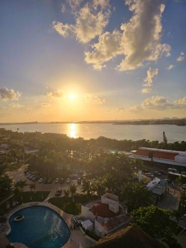 a view of a resort with the sun setting over the water at Laguna view and beach front cove at SALVIA CONDOMINIUMS in Cancún