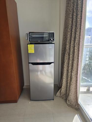 a microwave sitting on top of a refrigerator next to a window at Laguna view and beach front cove at SALVIA CONDOMINIUMS in Cancún