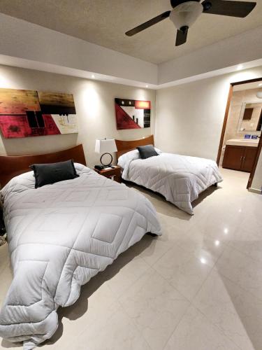 a bedroom with two beds and a ceiling fan at Laguna view and beach front cove at SALVIA CONDOMINIUMS in Cancún