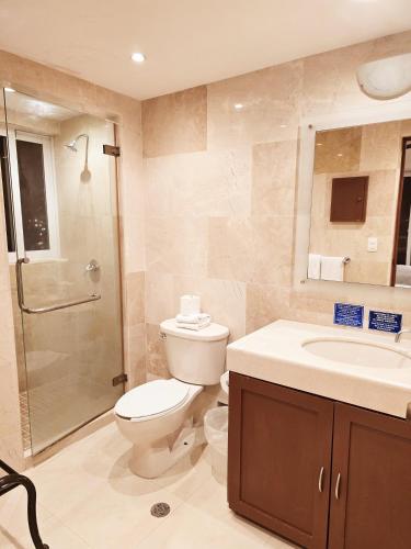 a bathroom with a toilet and a sink and a shower at Laguna view and beach front cove at SALVIA CONDOMINIUMS in Cancún