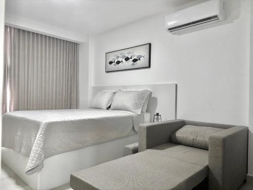 a white bedroom with a bed and a couch at UMI Flats - Intermares in Cabedelo