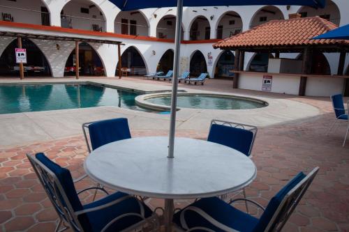 a table with chairs and an umbrella next to a pool at Hotel Hacienda Bugambilias in La Paz