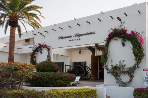 a white building with flowers and a palm tree at Hotel Hacienda Bugambilias in La Paz