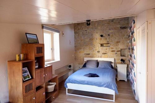 a bedroom with a bed and a stone wall at Chez Mathilde et Kévin in Saint-Maurice