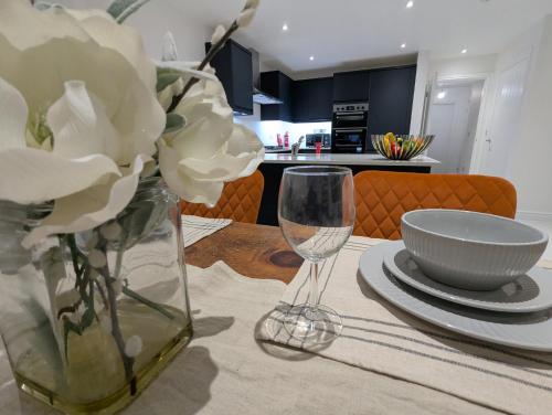 a table with a vase of flowers and a bowl and a glass at Large 4 Bed Hse, Sleeps 7, 3 BTH, Drive PRKG-4 Cars, M4-A329, Shinfield Studios, 10mins, Reading, Ascot & Legoland 20mins, Film Crew, Contractor & Family Friendly in Winnersh