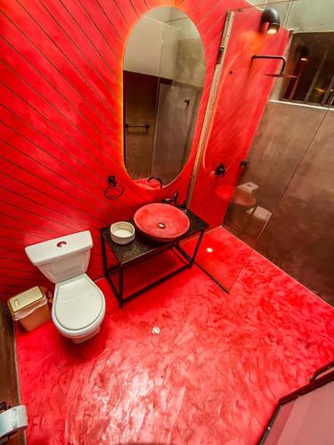 a red bathroom with a toilet and a sink at Antonia Poolside Autonomy Hotel in Ibagué