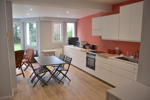 une cuisine avec des armoires blanches et une table et des chaises dans l'établissement KERJACNINE, à 300 m du port, maison 7 couchages avec grand jardin, au Pouliguen