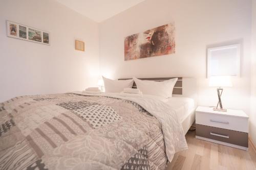 a white bedroom with a bed and a lamp on a nightstand at Waldperle in Altenau