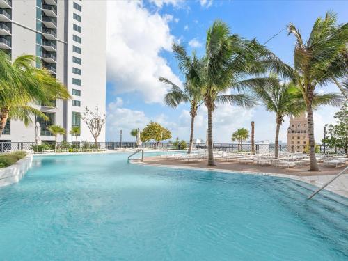 a swimming pool with palm trees and a building at Private Beach Club Access & Stunning Ocean Views in Miami