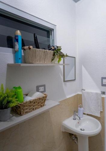 uma casa de banho com um lavatório e uma cesta numa prateleira em VillaOriental em San Miguel