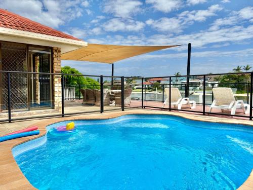 a swimming pool with a umbrella on top of a house at Waterfront Family House with Pool, BBQ in Gold Coast