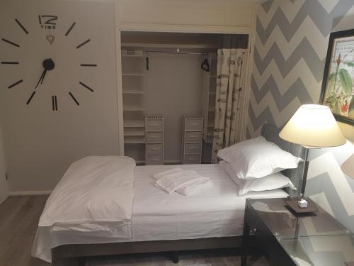 ein Schlafzimmer mit einem Bett mit einer Uhr an der Wand in der Unterkunft Spacious, Stylish Two-Bedroom Maisonette, Modern Amenities, Elegant Interiors in Buckinghamshire