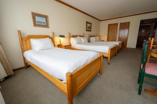 two beds in a room with two chairs at abba Presidente Suites Puerto Montt in Puerto Montt