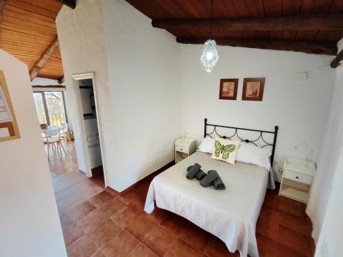 a bedroom with a white bed with two shoes on it at Las Casas de la Tía Sabina in Cortelazor