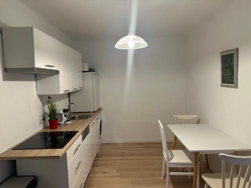 a kitchen with white cabinets and a table with chairs at Cheap Outlet Center Apartment with Pool in Parndorf