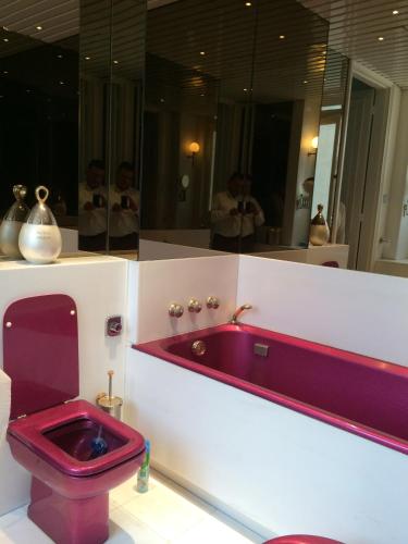 La salle de bains est pourvue de toilettes violettes et d'un miroir. dans l'établissement PLACE VENDOME 1 BR AND 1 BA - up to 4 people - WITH AIR CONDITIONNING, à Paris