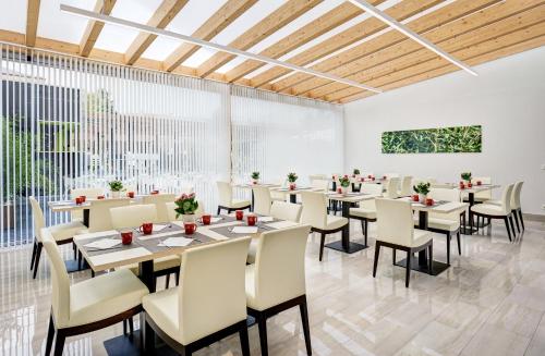 un comedor con mesas, sillas y ventanas en Sercotel Alcalá 611, en Madrid