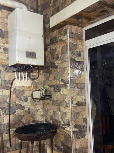 a kitchen with a stone wall with a table and a microwave at La belle vue in Bologuine Ibnou Ziri