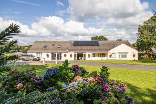 a house with a solar roof and some flowers at Lovesgrove Country Guest House in Pembroke Dock