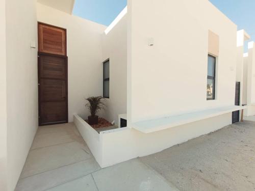 a white house with a door and a potted plant at Casa Apolo, piscina y club de playa in Chelem