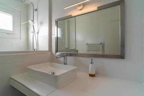 une salle de bain blanche avec un lavabo et un miroir dans l'établissement Fables du Jardin de la Fontaine, à Nîmes