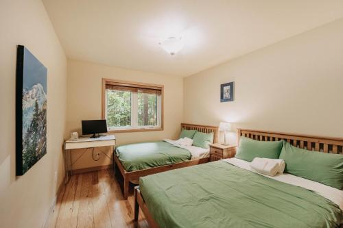 a bedroom with two beds and a desk with a computer at Mt Baker Lodging Cabin 40GS is a Classic NW cabin in Deming
