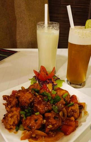 a plate of food on a table with two drinks at Sea Land Mandarmani in Mandarmoni
