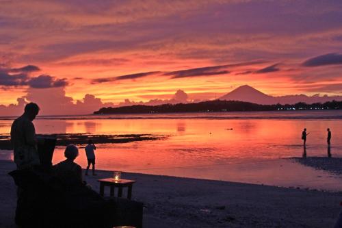 a group of people on the beach at sunset at Pandan Bungalow in Gili Air