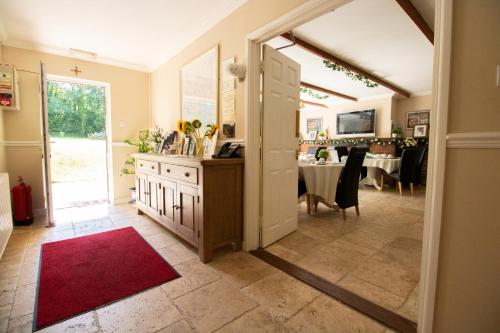 a hallway with a dining room with a red rug at Lovesgrove Country Guest House in Pembroke Dock