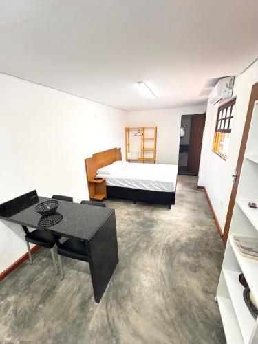 a room with a bed and a table in it at Recanto Vizinho do Mar in Ubatuba