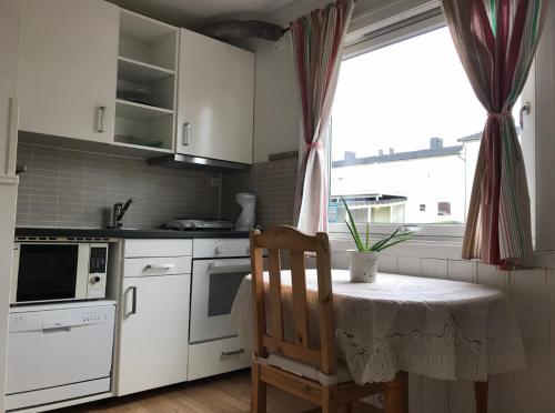 a kitchen with a table with a chair and a window at Cozy small bedroom flat in Trondheim