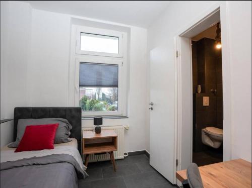 a bedroom with a bed with a red pillow and a window at Livemore24 - Space in Oer-Erkenschwick WLAN in Oer-Erkenschwick